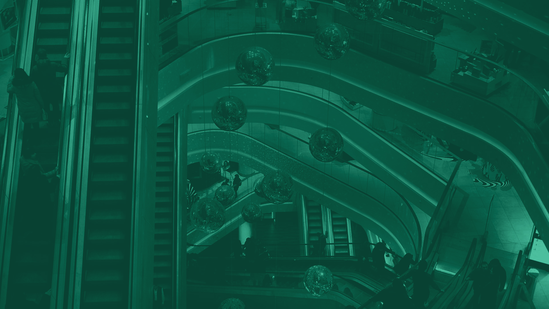 A photo of escalators and shoppers from the balcony inside of a multi-story shopping mall